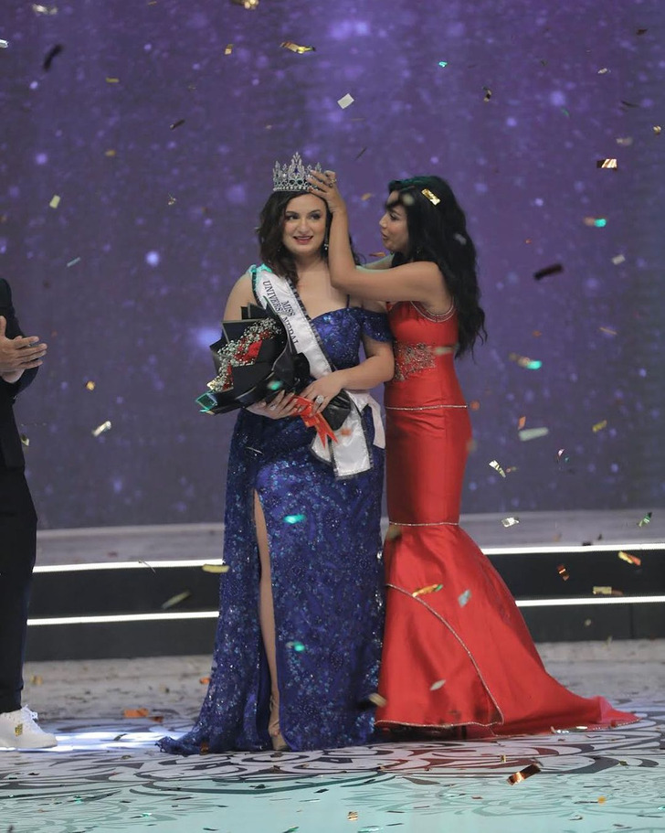A woman putting a crown in the head of the winner of a pageant constest.
