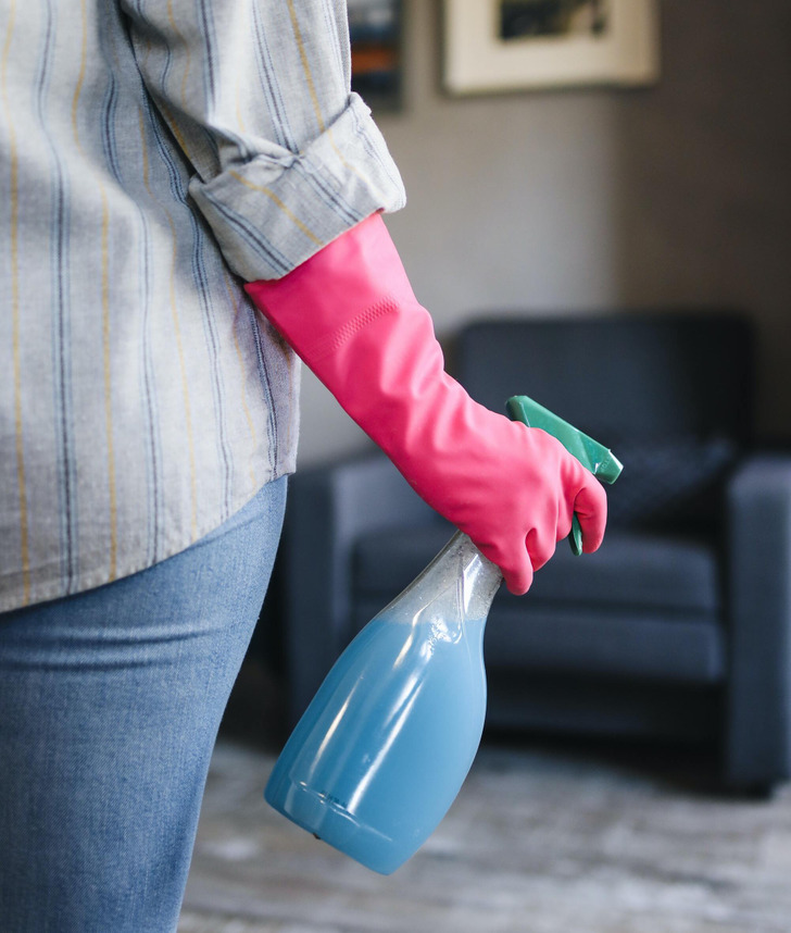 A close-up photo of a hand holding a bottle of cleaning product.