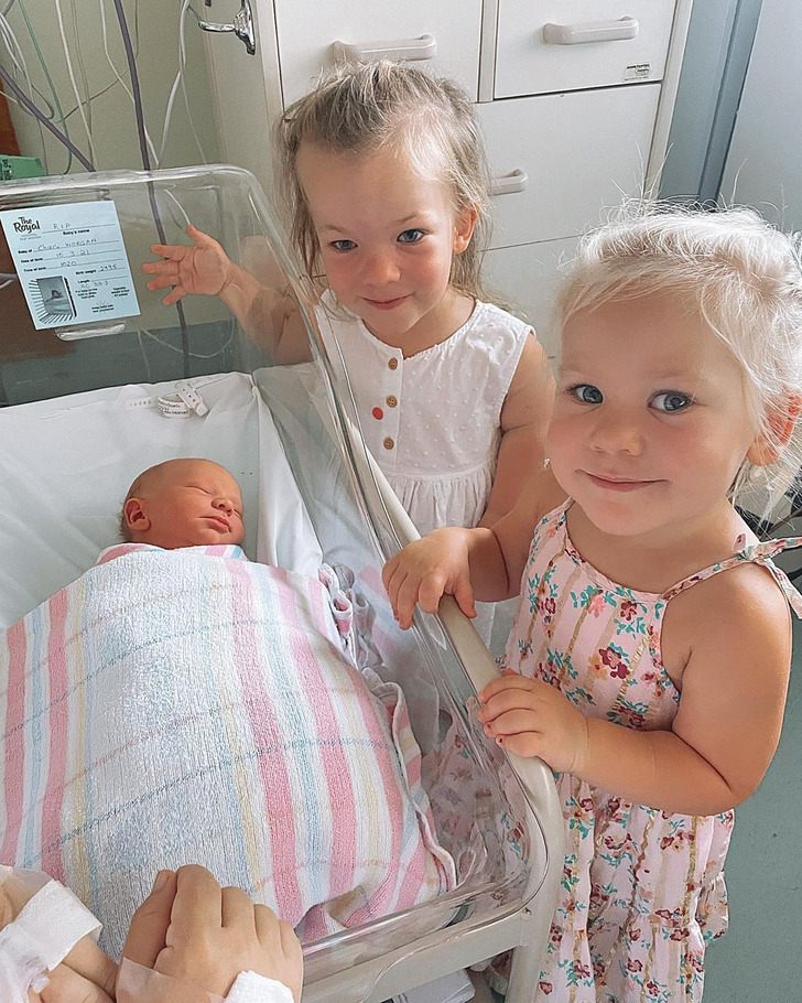 Two girls in a hospital beside a baby that was just born.
